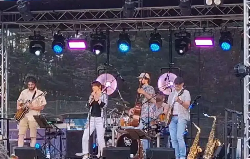 Le groupe sur une grande scène en plein air, sous les projecteurs